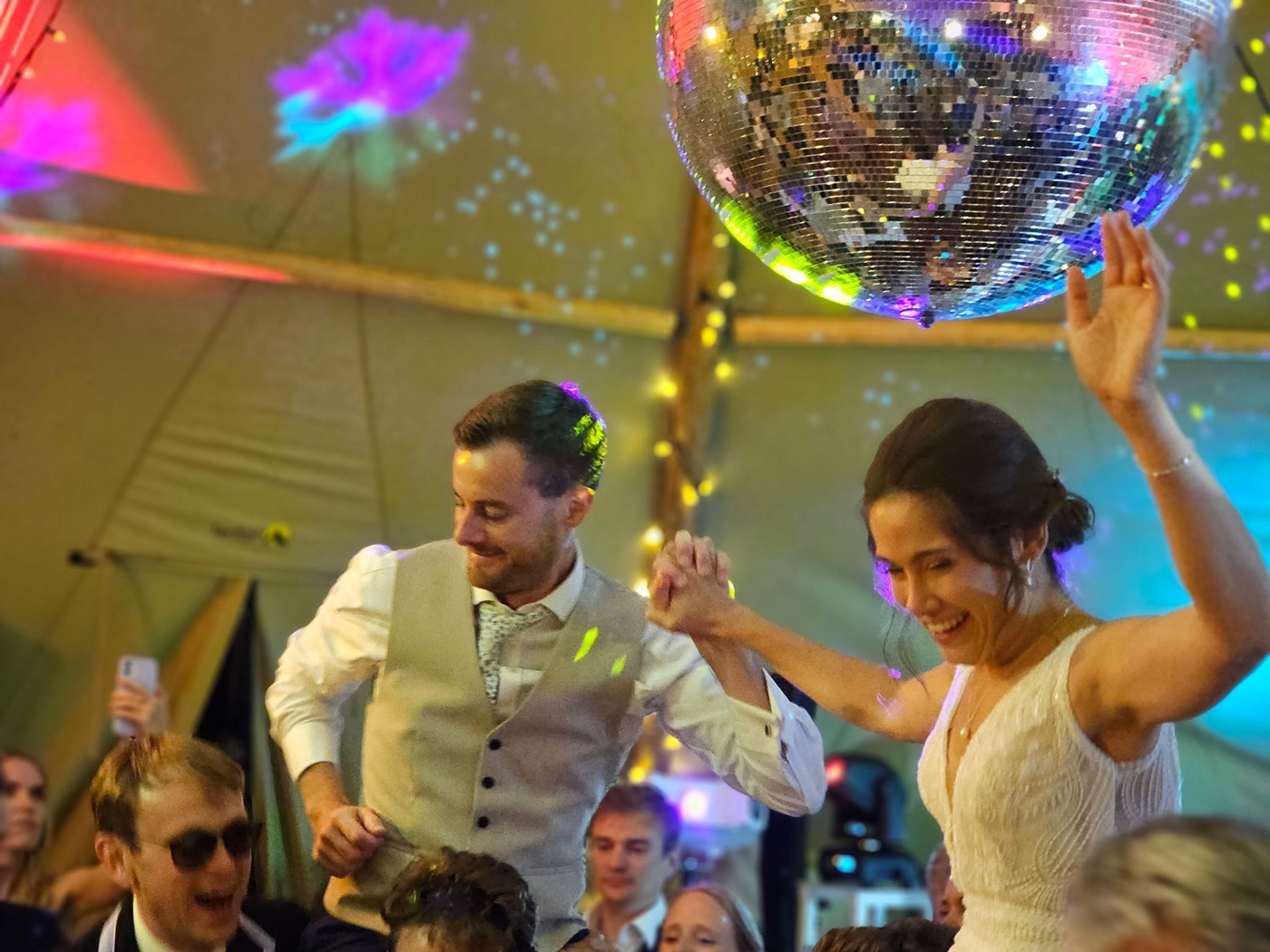 Bride and groom dancing under warm mirror ball lighting